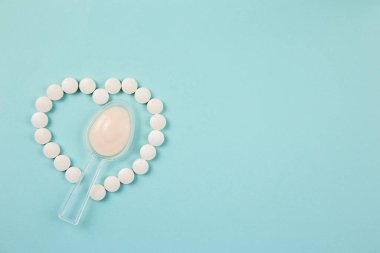 Antibiyotik alırken bağırsaklarınızdaki iyi bakterileri iyileştirmek için de probiyotik almalısınız. Antibiyotikler ve probiyotik konsepti arasındaki denge. Probiyotik haplardan yapılmış kalp ve antibiyotik dolu kaşık..
