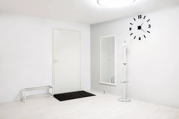 Empty hallway entrance with few furnishing elements, white and gray walls and flooring.