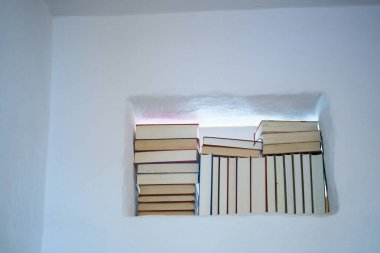 Parlak ve güneşli bir kitap yığınının ayrıntıları bir kırsal kesimin beyaz duvarında modern yaşamın dokulu bir duvarında, kopyalama alanı.
