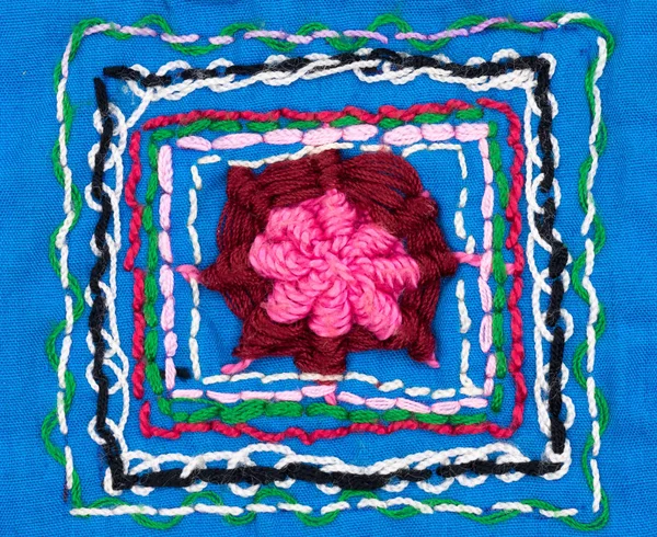 Closeup handmade embroidery design on blue fabric