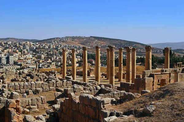 Ürdün 'ün Jerash kentindeki antik Roma şehrinin tepesinden, yazın modern Orta Doğu şehrinin arka planına bakın..