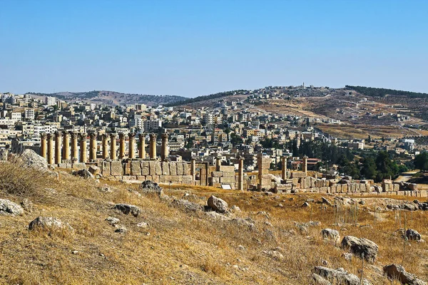 Ürdün 'ün Jerash kentindeki antik Roma şehrinin tepesinden, yazın modern Orta Doğu şehrinin arka planına bakın..