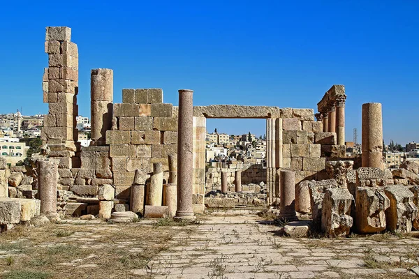 Ürdün 'ün Jerash kentindeki antik Roma şehrinin tepesinden, yazın modern Orta Doğu şehrinin arka planına bakın..
