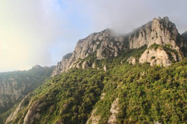   ,             .     .Montserrat bir Benedikt manastırı, bir ruhani sembol ve Katalonya 'nın dini merkezi ve dünyanın dört bir yanından gelen Katolikler için bir hac merkezidir. Bulutlarla kaplı bir manastırın çarpıcı manzarası.
