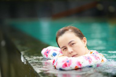 Asyalı kadın havuz kenarında dinleniyor. Portre tatilinde kameraya bak.