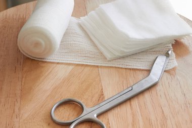 Giyinme ya da temiz yara aletleri arasında sargı bezi, sargı bezi ve sargı bezi yığını veya güneş ışığıyla kesilmiş makas yer alıyor.