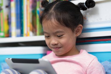 Asyalı Taylandlı çocuk kendini tablet okumaya kaptırmış.