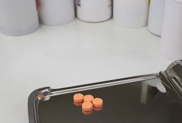 ドラッグストアの麻薬トレイを半分に数える4台のオレンジの医療用錠剤 — ストック写真