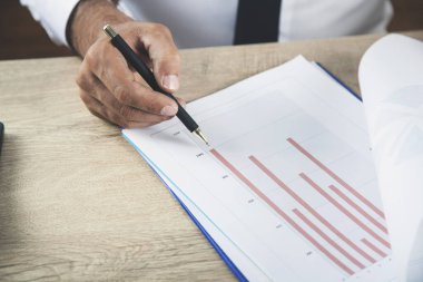 Adam el kalemi ve masanın üstünde grafik.