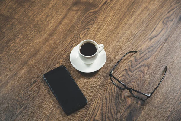 phone with glasses and coffee on desk