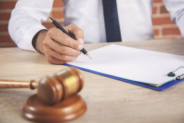 Adam ahşap yargıcın elinde ve masasında belge var.