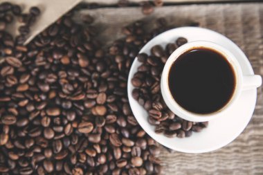 Kahve taneleri ve kahve fincanları masanın üstünde.