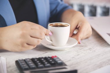 İş kadını masasında bir fincan kahve.