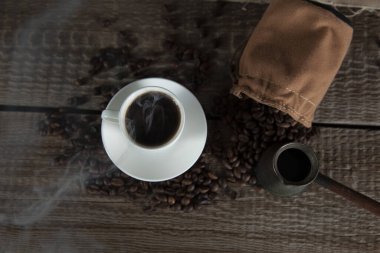 Kahve taneleri ve kahve fincanları masanın üstünde.