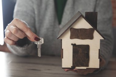 Kadın el anahtarı, arka planda ev modeli.