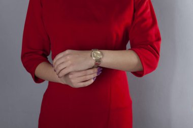 Gri arka planda el ele tutuşan şık bir kadın.