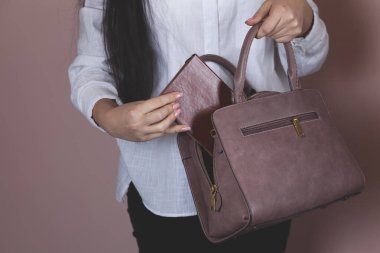 Pembe arka planda çantalı bir kadın el bilgisayarı.