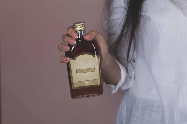 Donna Mano Possesso Bottiglia Brandy Sfondo Rosa — Foto Stock