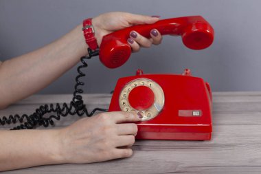 Gri arka planda kırmızı telefon tutan kadın.