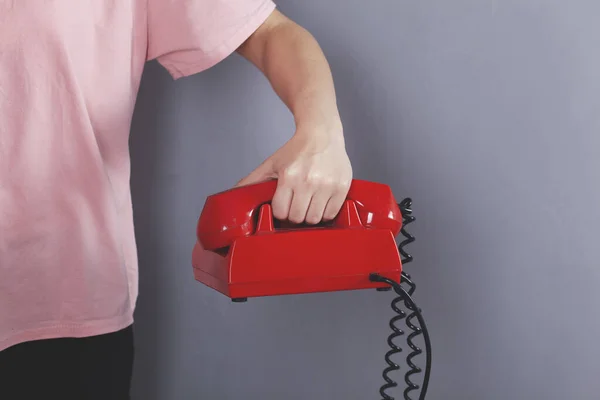 グレーの背景に赤のヴィンテージ電話を持っている女性の手 — ストック写真
