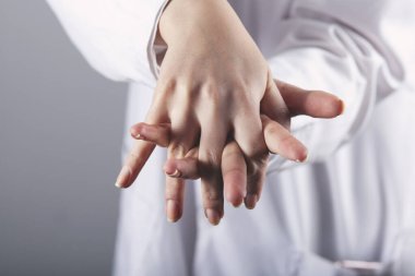 Doktor ellerini gri arka planda jel ile yıkıyor.