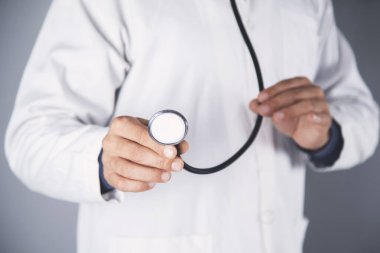 Doktor el steteskobu gri duvar arkasında.