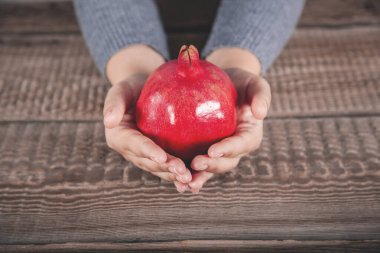 Ahşap masa arkasında kadın eli nar.