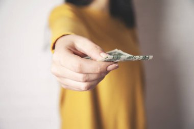 Genç kadın pembe arka planda para dağıtıyor.