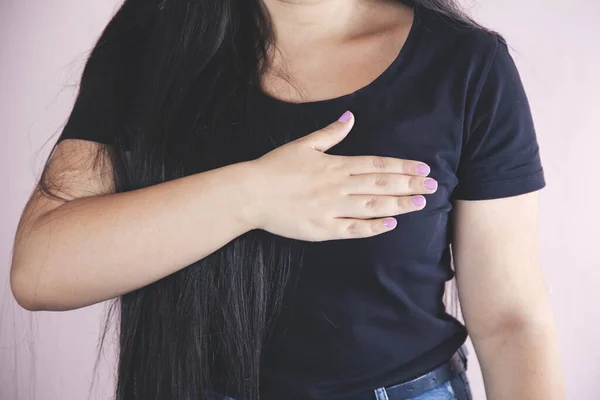 woman hand in ache heart on pink background