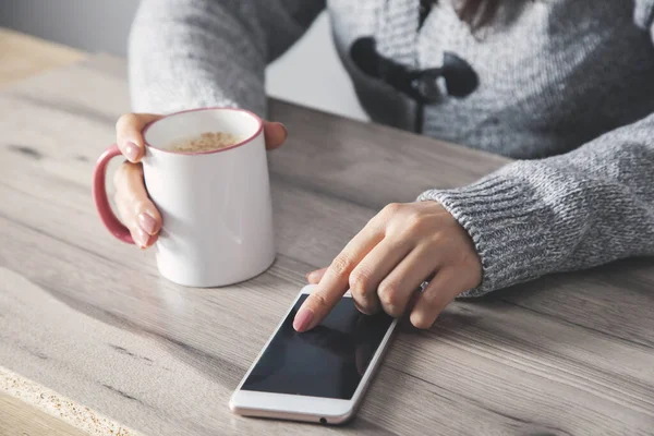 woman hand smart phone with cup of coffee on the desk