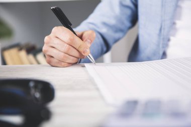 Masasında belge olan erkek eli kalem.