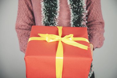 Kadın, gri arka planda kırmızı hediye kutusu.