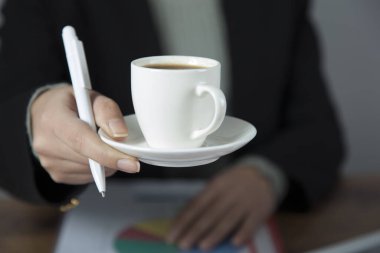 Masasında belge olan bir fincan kahve.