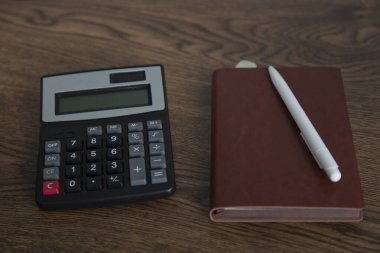Masasında hesap makinesi olan not defterine kalem.