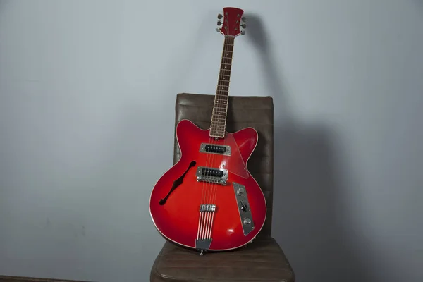 red guitar on the chair on gray background