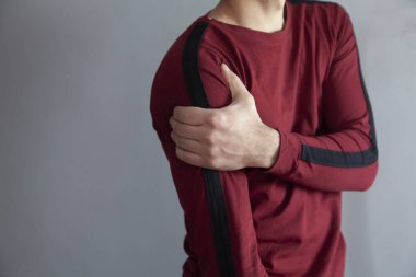 Gri duvar arka planında omuz ağrısı var.