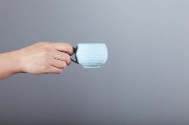 Bir fincan çay ya da kahve tutan bir kadın.