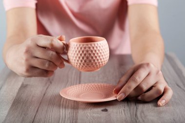 Kadın eli çay ya da kahve masanın üstünde.