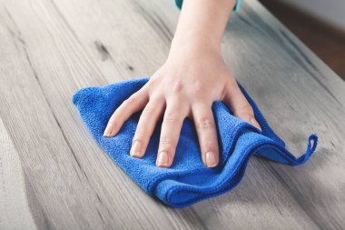 Ahşap masa arkasını temizleyen genç bir kadın 