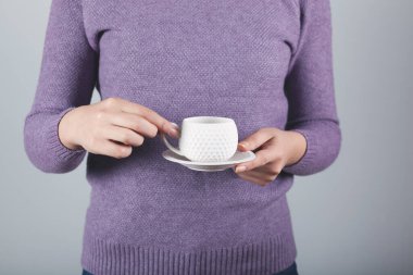 Bir fincan kahve ya da çay tutan bir kadın. 