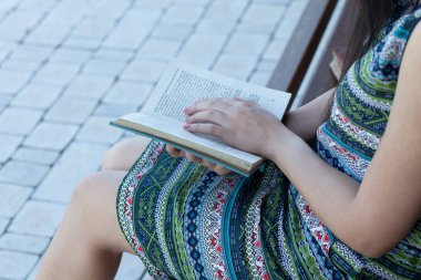 Sokakta kitap okuyan genç bir kadın.