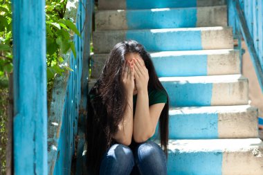 Üzgün kadın başbaşa merdivenlerde oturuyor.