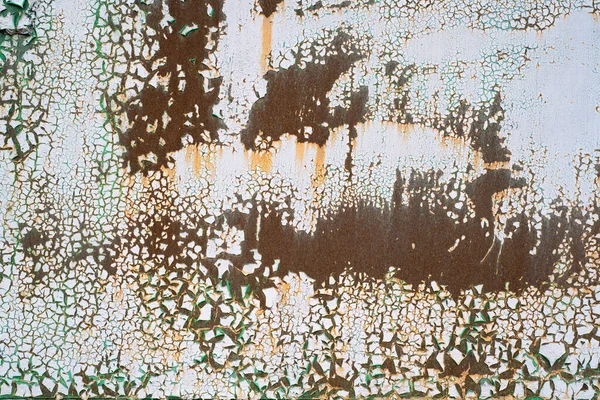 Painted metal with cracks in the paint, roughness. Cracking and flaking paint on rusty iron background. Close-up of a metal or steel plate, covered with old paint. Detailed photo texture.
