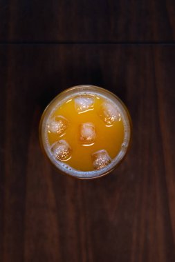 Tahta masada buz küpleriyle taze sıkılmış portakal suyu.