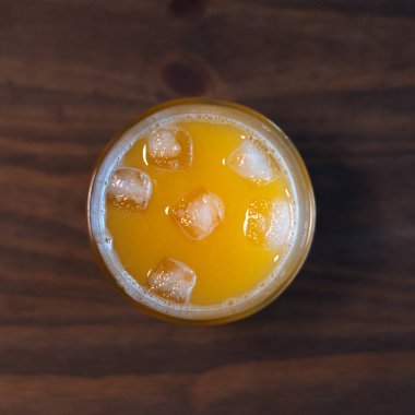 Tahta masada buz küpleriyle taze sıkılmış portakal suyu.