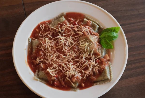 Domates soslu vejetaryen panzotti ve ahşap masada mantar.