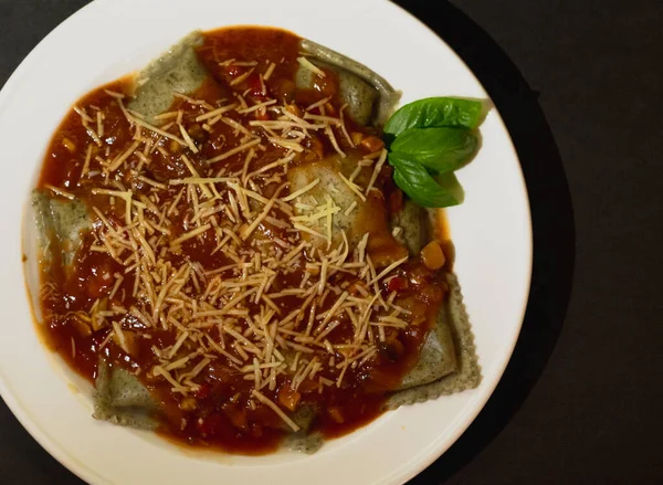 Domates soslu vejetaryen panzotti ve siyah arka planda mantar.