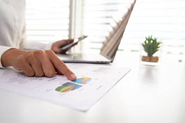 Ofiste dizüstü bilgisayarın önünde oturan bir iş kadını. İş görüşmesi yöneticilerinin özet grafik istatistiklerinden veri analizi kavramı. Grafik, istatistik, finans, yönetim, muhasebe.