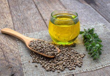 CBD kenevir yağı cam şişede. Kenevir tohumu tahta kaşıkta. Kenevir yaprağı masaya konur. Tıbbi amaçlar için esrar kavramı. Kenevir yağı çıkarma bileşenleri. Alternatif tıp..