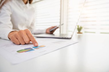 Ofiste dizüstü bilgisayarın önünde oturan bir iş kadını. İş görüşmesi yöneticilerinin özet grafik istatistiklerinden veri analizi kavramı. Grafik, istatistik, finans, yönetim, muhasebe.